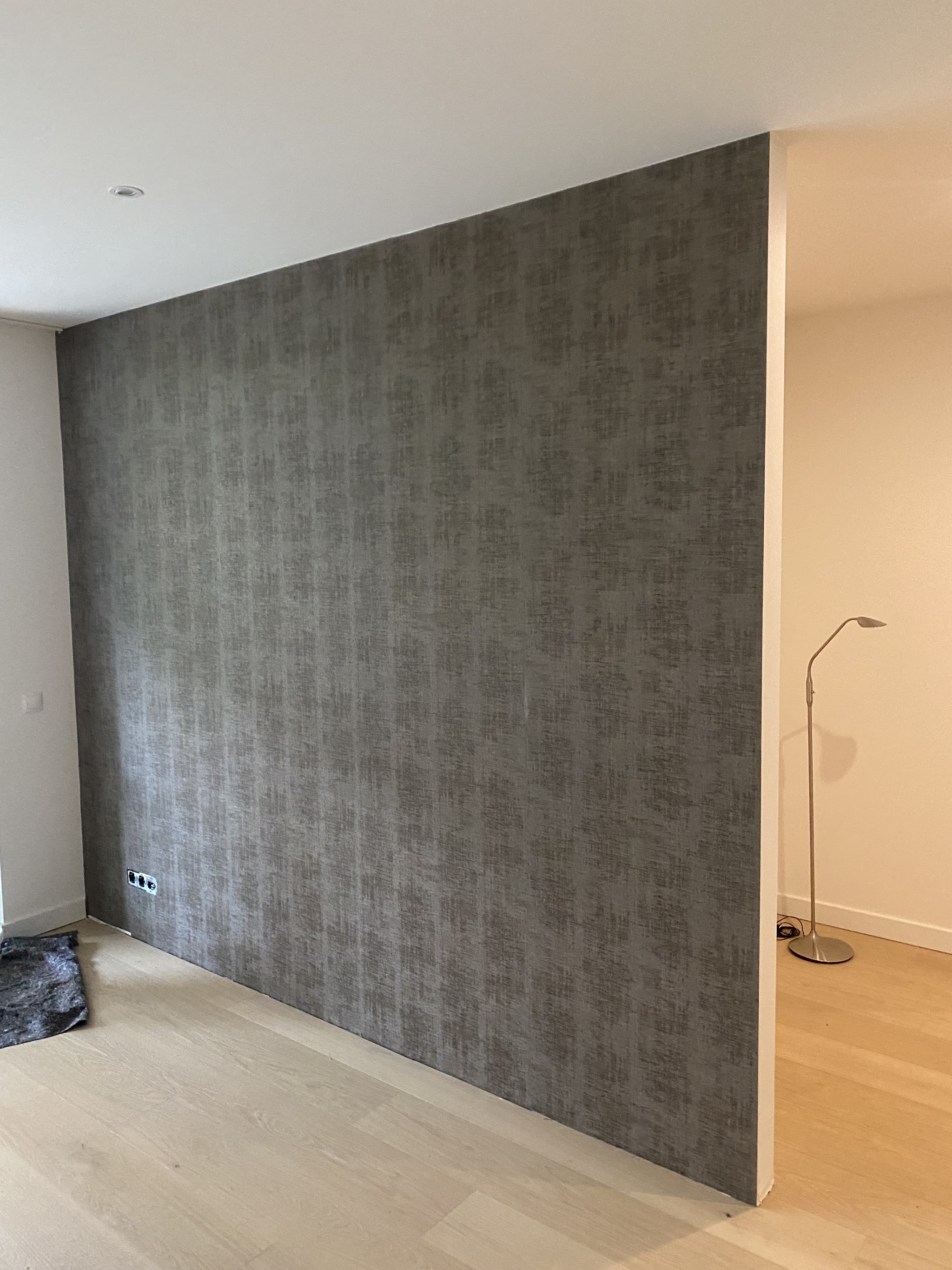 Een wand met donker structuurbehang in een lichte kamer